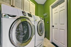 Small bright green laundry room inter with washer and dryer.