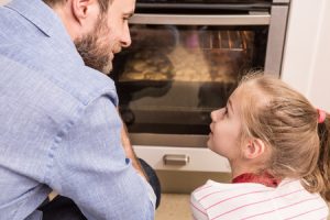 father and daughter waiting near the kitchen oven