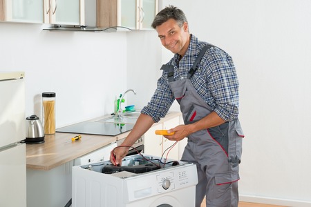 technician checking washing machine with digital multimeter