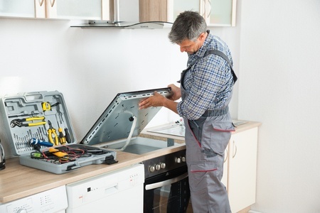 repairman examining stove in kitchen