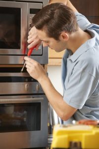 repairman fixing the microwave in the kitchen