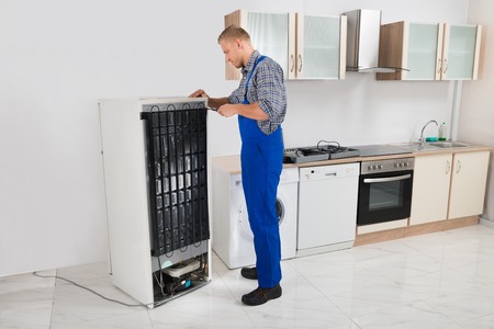 technician repairing refrigerator in kitchen room