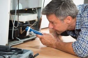 technician checking the refrigerator with flashlight