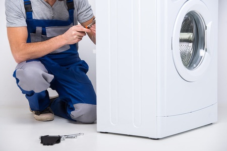 repairman is repairing a washing machine