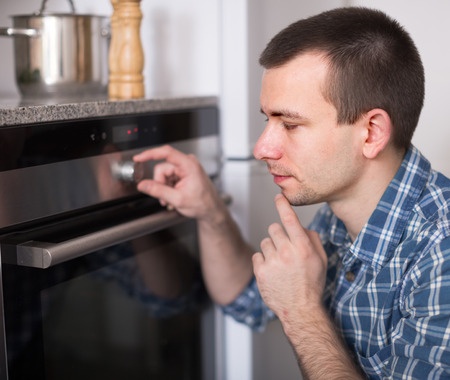 oven repairman checking the controls